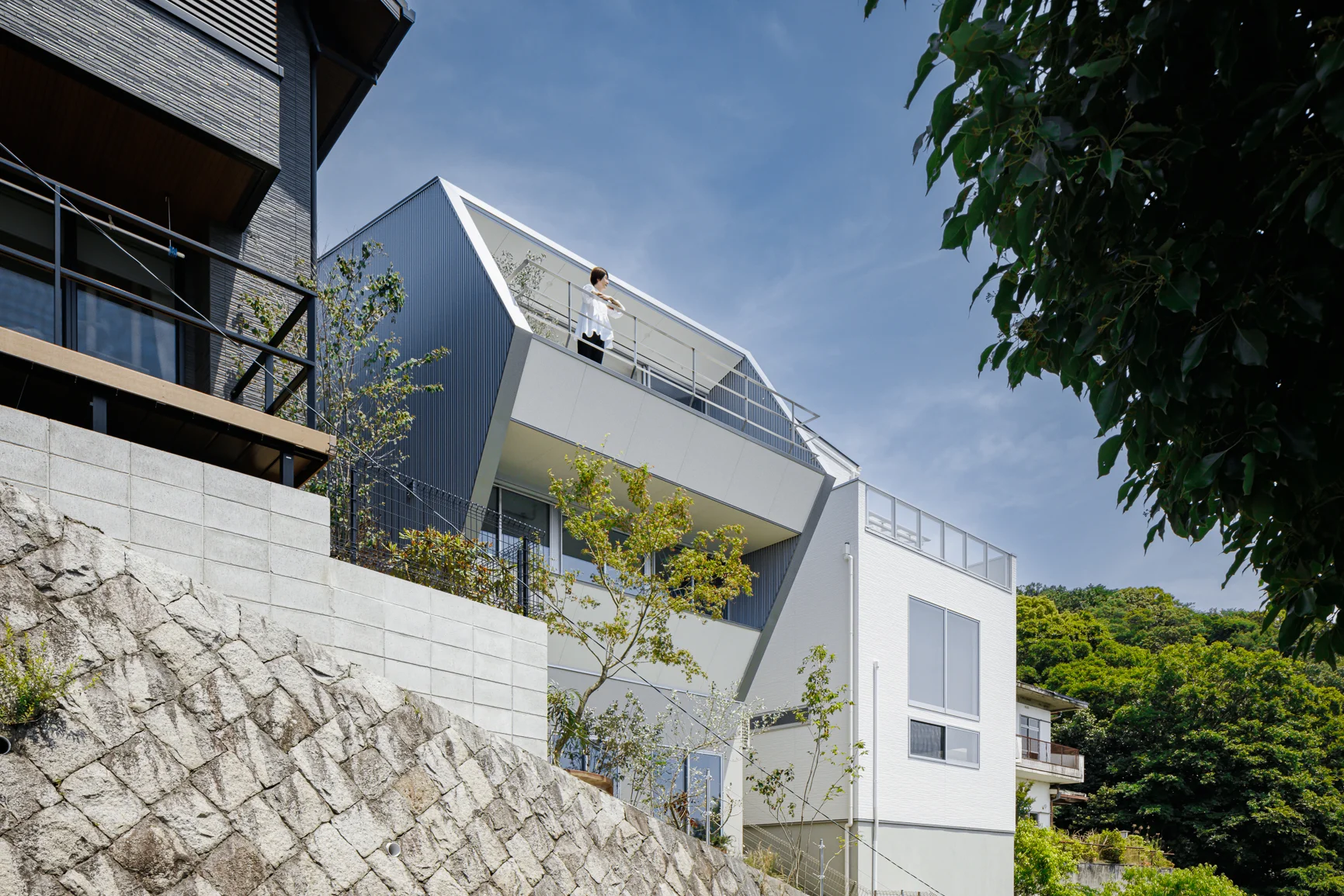 傾斜地に建つバルコニーのある住宅の外観