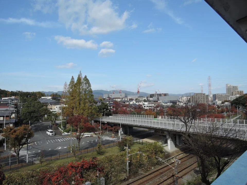 吹田の家：現地から見下ろす線路と道路、色づいた木々や遠くの街並み