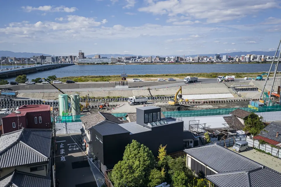 海老江の家。淀川と対岸の街並みを背景に、住宅街に建つ家を上空から望む