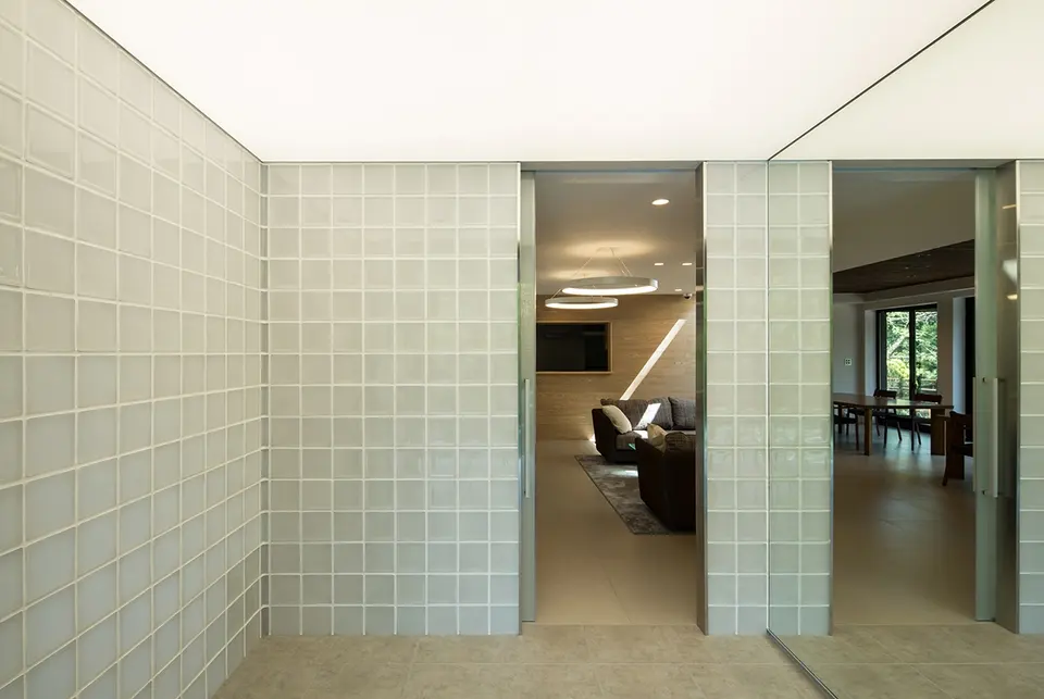 亀岡のVILLA／保養所。ガラスブロックの壁と大きな鏡を配した玄関ホールから、室内へつながる入口を望む