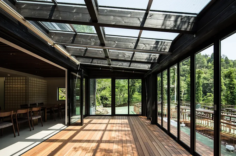 亀岡のVILLA／保養所。ガラス屋根から日差しが入り、周囲の緑を見渡せる木の床のサンルーム
