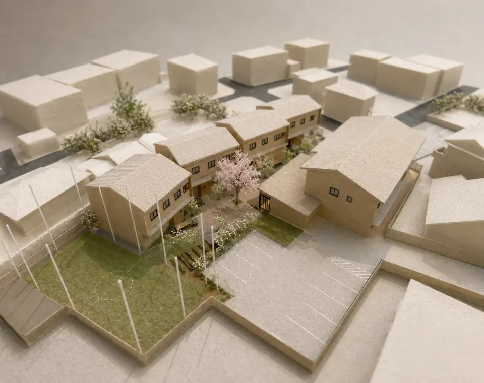 名古屋の児童養護施設の建築模型。複数の建物と植栽のある中庭、芝生の広場、駐車場の配置を上から望む。