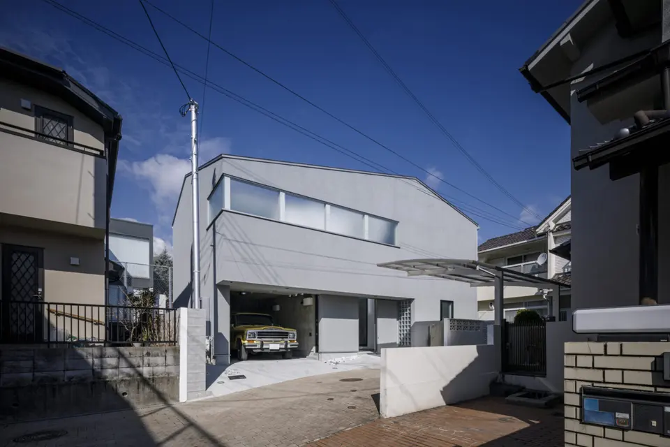 宝塚のライトコートハウス。住宅街に建つグレーの外観。横長の窓と、車を収めたビルトインガレージ。