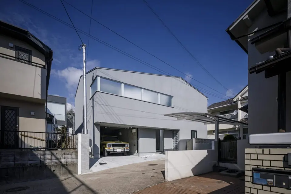 宝塚のライトコートハウス。住宅街に建つグレーの外観。横長の窓と、車を収めたビルトインガレージ。